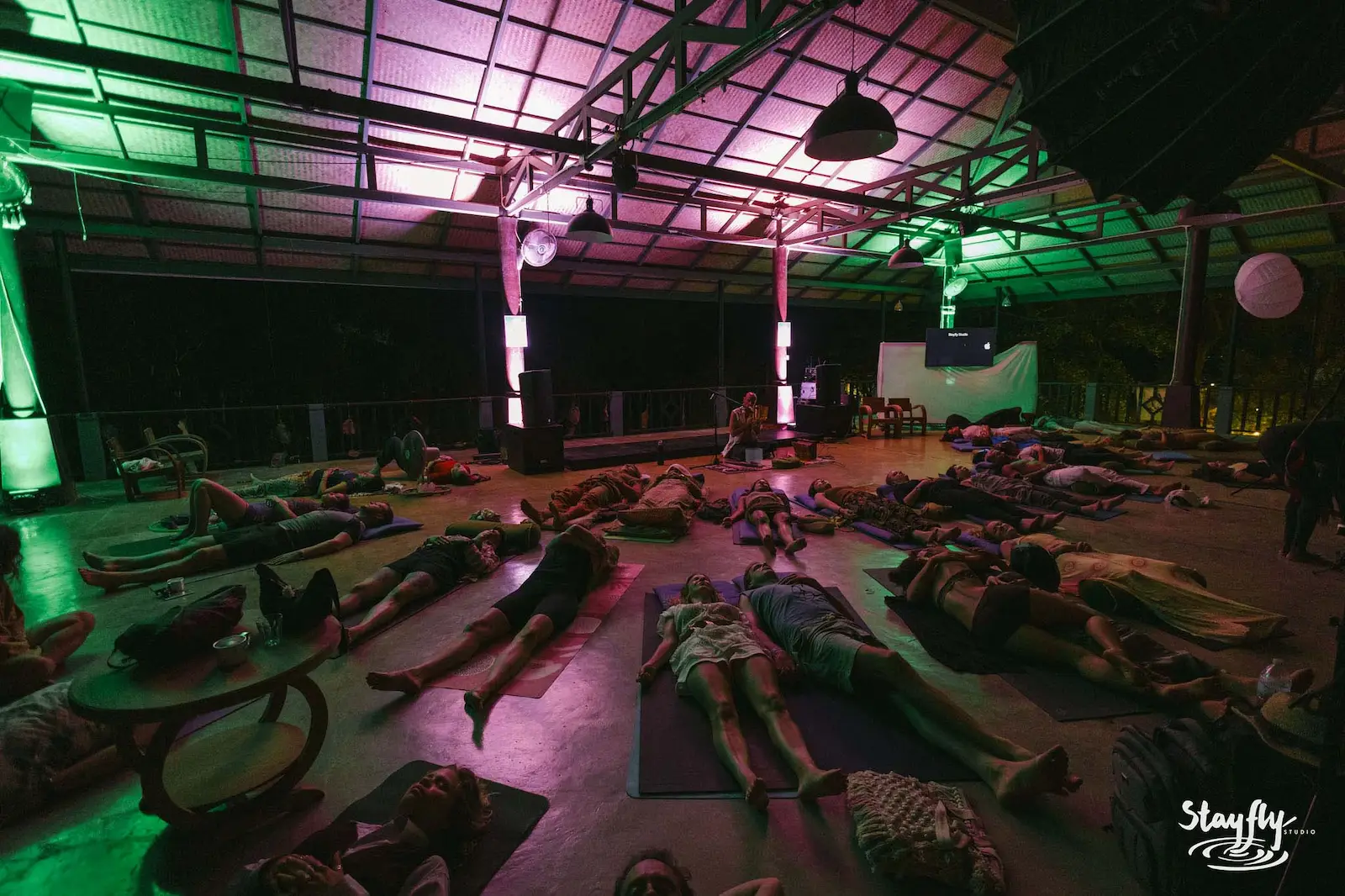 People lying on mats in Yoga Hall under green light.